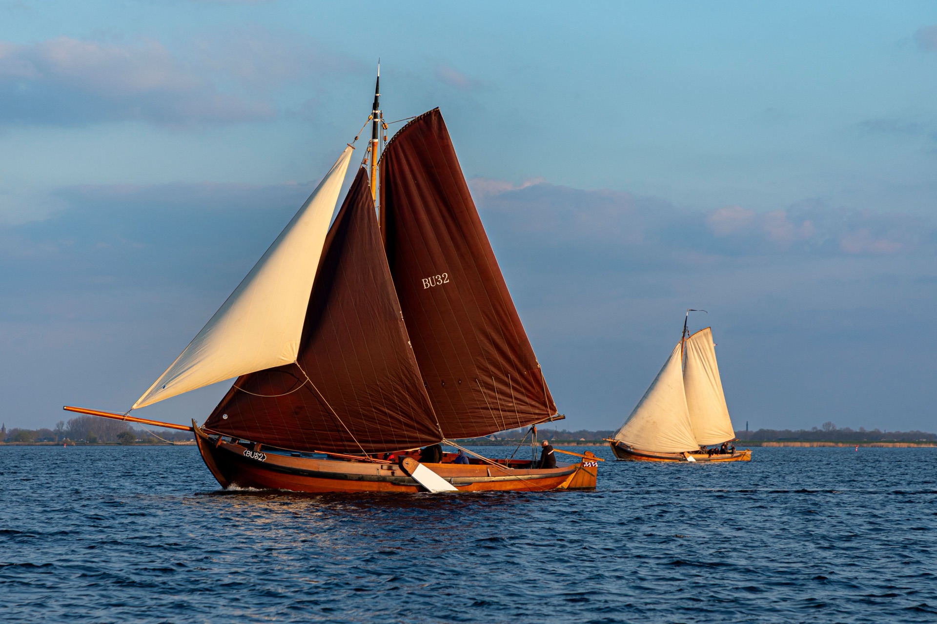 Traditionele Nederlandse platbodems met bruine zeilen op het water